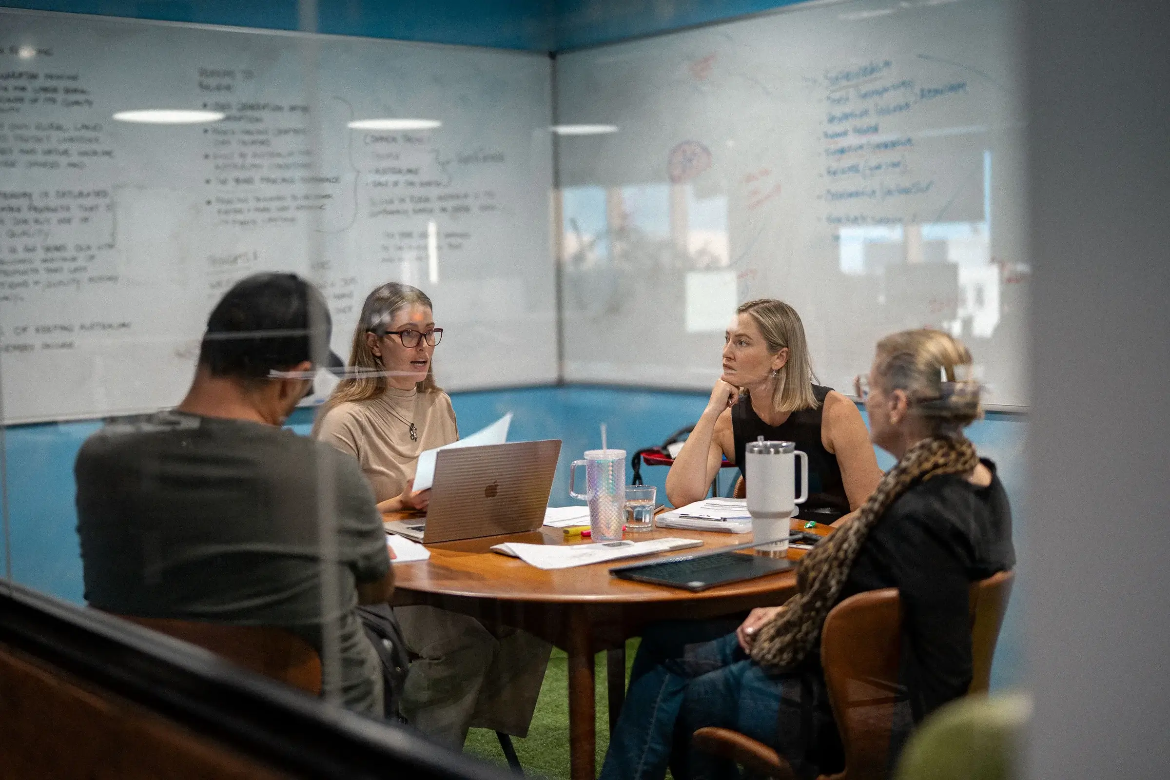 staff sitting around table in small glass room
